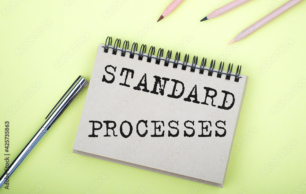 Poster standard processes text on the notebook with pen on yellow background