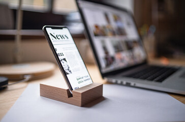 Smartphone in wooden stand holder on table indoors at home or on office.