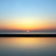 Fototapeta na wymiar reflection of colorful sunset in water near beach