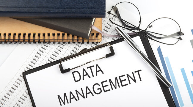 Text DATA MANAGEMENT on Office desk table with notebooks, supplies,analysis chart, on white background. Top view