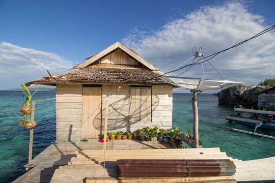 Unidentified  common wooden house with satellite and flowers in pots with the ocean behind