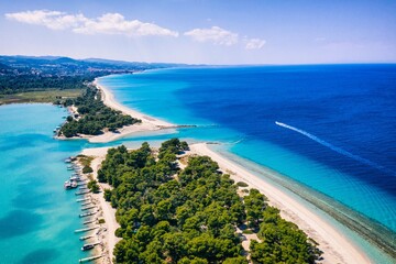Fototapeta premium Beautiful Beach With Golden Sand And Clear Water. Turquoise coast with blue water and golden sand in Europe. Summer vacation background with turquoise sea water bay and pine trees aerial drone photo