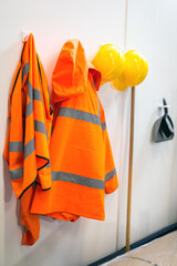 High visibility protective clothing and hard hats hanging up in a warehouse for easy access for the workers. Warehouse, stores, safety gear concept