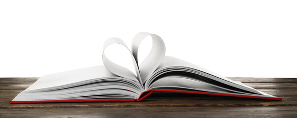 Open book with pages folded in heart on wooden table against white background