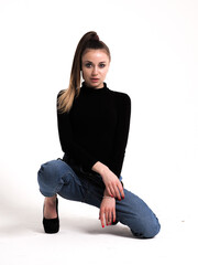 The brunette on a white background in a bodysuit and jeans with heels and a ponytail