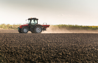 Obraz premium Tractor spreading artificial fertilizers in field