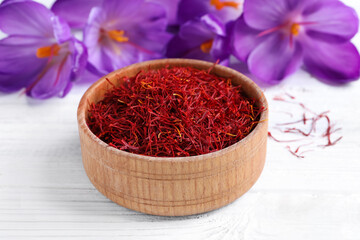 Dried saffron and crocus flowers on white wooden table, closeup