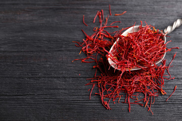 Dried saffron on black wooden table, closeup. Space for text