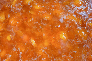 Texture, background of apricot jam. Orange fruit. Home-made for the winter. The view from the top.