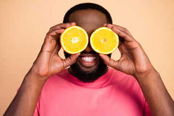 Photo portrait of man keeping juicy oranges organic fruits hiding eyes behind isolated pastel beige color background