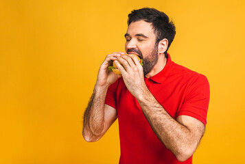 Young man holding a piece of sandwich. Student eats fast food. Burger is not helpful food. Very...