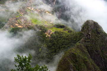 view of Machu Picchu from the top of the hill through the clouds 