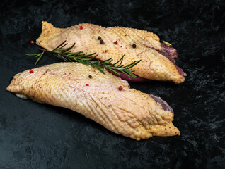 Raw fillet of farm eco duck on a black textured background.