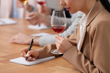 Sommeliers tasting different sorts of wine at table indoors, closeup