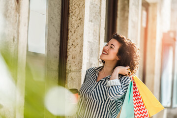 Naklejka premium Young woman walk outdoors with coffee cup and shopping bags after shopping