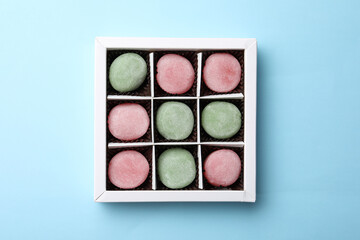 Many different delicious mochi in box on light blue background, top view. Traditional Japanese dessert