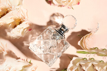 Bottle of aromatic perfume and flowers on beige background, flat lay