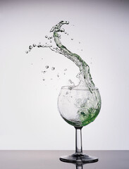 a big splash of green drink in a glass 