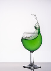 a big splash of green drink in a glass 