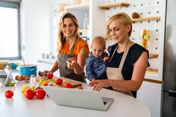 Portrait of female couple in the kitchen with their daughter