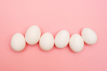 White chicken eggs on pink background