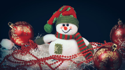Toy snowman with festive red ball on a black background