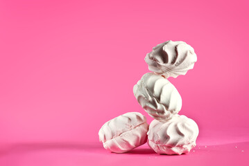 Marshmallow candies fall on a pink background. Sweets close up. The concept of childhood and holidays. Copy space and free space for text near sweets.