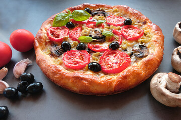  Homemade vegetarian pizza with mushrooms, olives,tomatoes, Basil and cheese on a dark background. Concept-healthy food