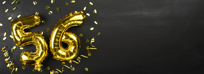 gold foil balloon number fifty six. Birthday or anniversary card with the inscription 56. Black concrete background. Anniversary celebration. Banner.