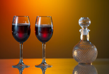 Two glasses of red wine are placed on a table with a reflective surface. sunset background. summer mood