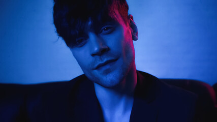 man in blazer looking at camera on blue