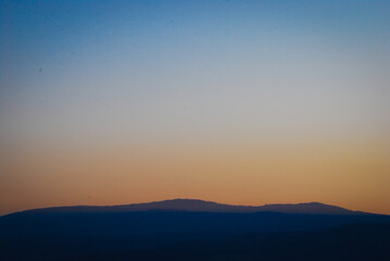 Mountain silhouette in dusk showing blue to orange sky gradient background