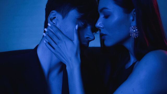 seductive woman embracing man in blazer on blue