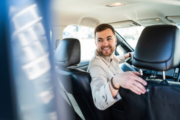 Smiling man driving in reverse on car
