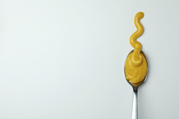 Spoon with mustard sauce on white background