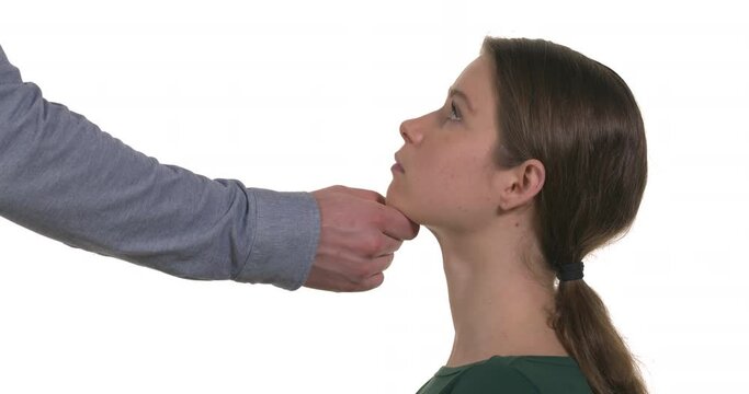 Side view of young Caucasian woman and man's hand touching her chin. Physical and sexual harassment in workplace. Isolated on white background