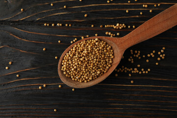 Wood spoon with mustard seeds on wooden background