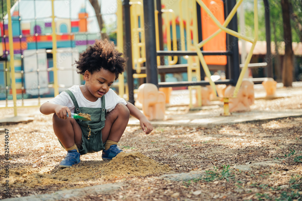 Wall mural Black people African American child playing sand in playground