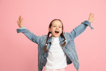 Happy kid, girl isolated on pink studio background. Looks happy, cheerful, sincere. Copyspace. Childhood, education, emotions concept