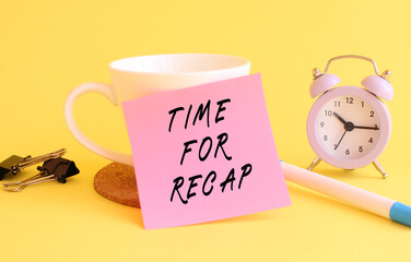 Pink paper with the text TIME FOR RECAP on a white cup. Clock, pen on a yellow background.