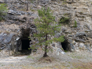 Abandoned industrial mines entrance, dark spooky asbestos shaft in rock, dangerous urban exploration, asbestos cancers