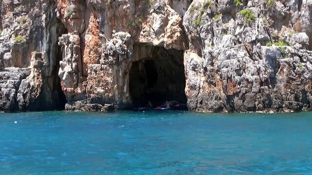 Canoeists visiting some of the enchanting grottos where can have a rest and cool down as well. Palinuro coastline, Italy. 