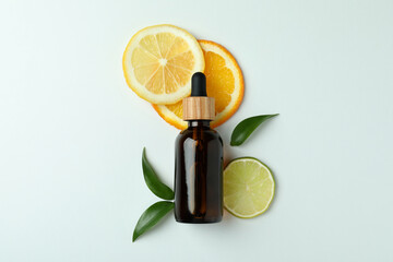 Dropper bottle with oil and citrus slices on white background