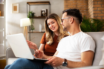 Happy young couple with laptop at home. Boyfriend and girlfriend using laptop