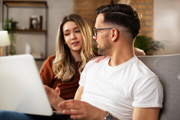 Happy young couple with laptop at home. Boyfriend and girlfriend using laptop