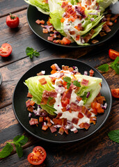 Iceberg wedge salad with bacon, cherry tomatoes, red onion and dressing. healthy food