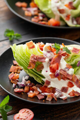 Iceberg wedge salad with bacon, cherry tomatoes, red onion and dressing. healthy food