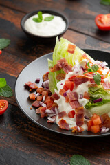 Iceberg wedge salad with bacon, cherry tomatoes, red onion and dressing. healthy food