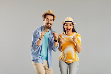 Portrait of attractive charming cheerful couple in summer hat emotional rejoicing with raised fist. Cheery glad people celebrating great holiday vacation having fun isolated on studio background