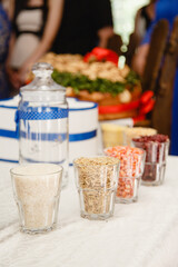 Details of wedding ceremony and tradition of making family amulet from different grain, indoor. Blue decorations in the wedding celebration. Wedding couple making their own family amulet together. 